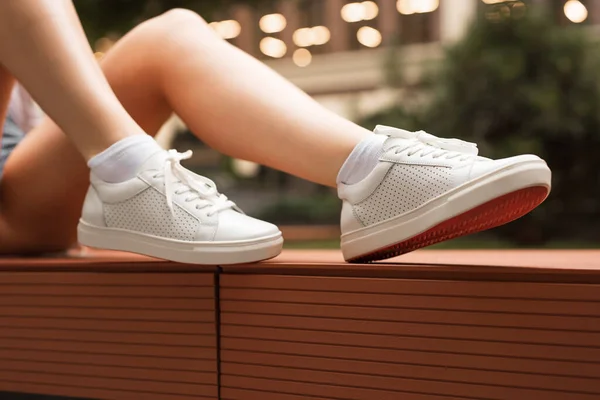 Sapatilhas de couro perfuradas brancas em pernas femininas — Fotografia de Stock