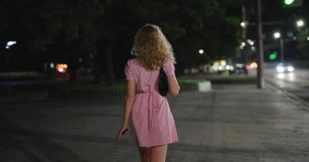 Sexig kvinna i klänning går på natten stad och vända tillbaka — Stockvideo