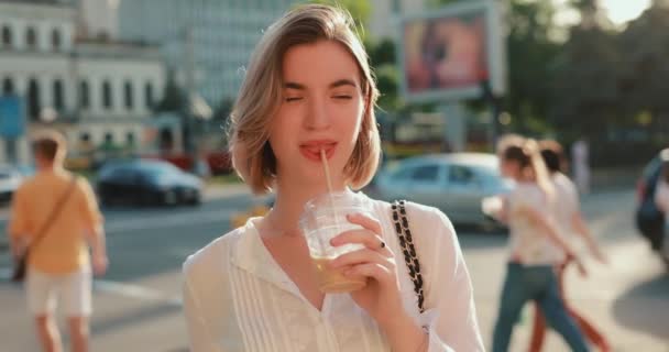 Щаслива жінка п'є холодний латте в місті — стокове відео