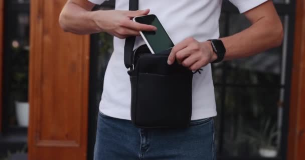 Felismerhetetlen ember tesz mobiltelefon egy futár táska — Stock videók