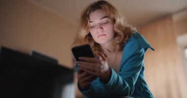 Evde yatakta cep telefonu kullanan güzel bir kadın.