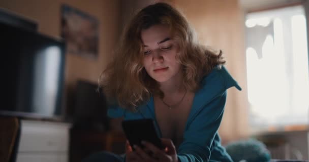 自宅のベッドに座って携帯電話を使用して美しい女性 — ストック動画
