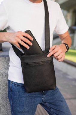 Tanınmayan adam çantayı kurye çantasına koyar.