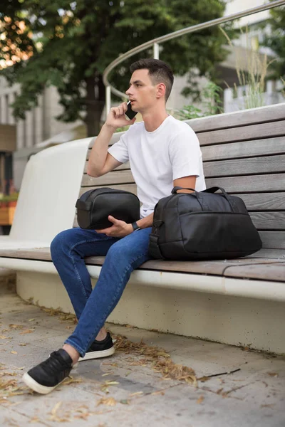 Uomo di moda seduto su una panchina in possesso di borse — Foto Stock