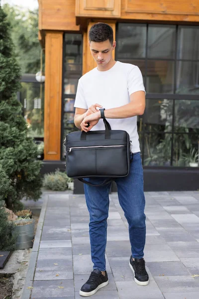 Un hombre camina alrededor de la ciudad sosteniendo la bolsa en su mano —  Fotos de Stock