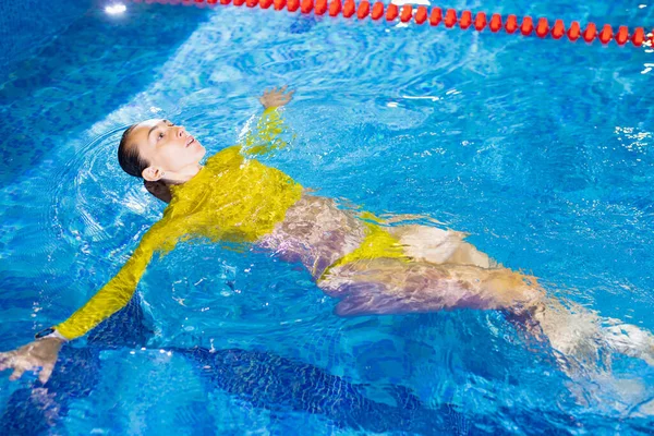 Mulher nada de costas na piscina interior — Fotografia de Stock