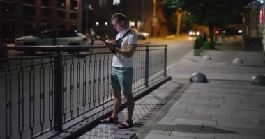 Gece şehirde cep telefonu kullanan bir adam.