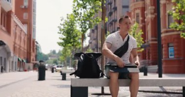 Serbest çalışan bir adam şehirde dizüstü bilgisayar açıyor ve kullanıyor.