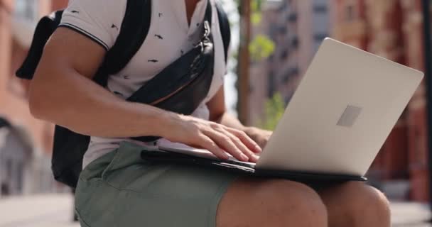 Nerozpoznatelný muž otvírá a používá notebook sedící ve městě — Stock video