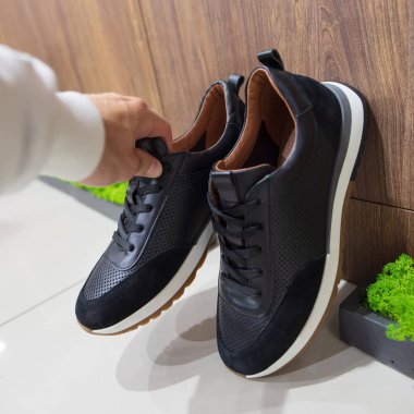 Pov erkek eli ayakkabı mağazasında yeni bir siyah spor ayakkabı seçiyor.