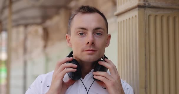 El hombre se pone grandes auriculares en una ciudad — Vídeo de stock