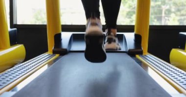 Spor salonunda koşu bandında koşan bacaklar.