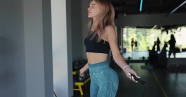 Kadın salonda ip atlıyor.