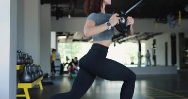 Genç bir kadın spor salonunda çömeliyor.