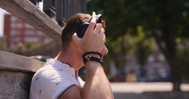 Muž nasadí velká sluchátka v parku — Stock video