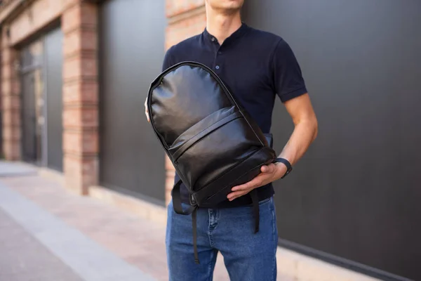 Mann hält und demonstriert seinen neuen schwarzen Lederrucksack — Stockfoto