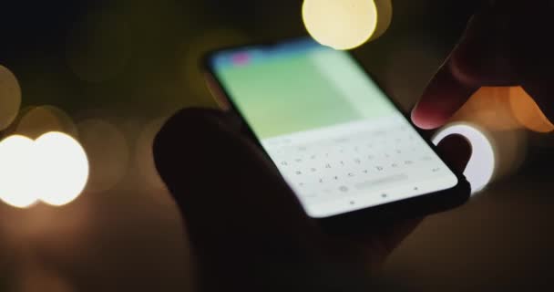 Mężczyzna ręka sms wiadomość w telefon komórkowy w nocy miasta — Wideo stockowe