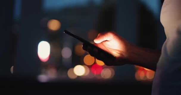 Άνδρας χέρι χρησιμοποιώντας το κινητό τηλέφωνο σε μια νυχτερινή πόλη — Αρχείο Βίντεο