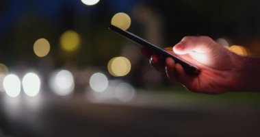 Bir gece şehrinde cep telefonu kullanan bir erkek.