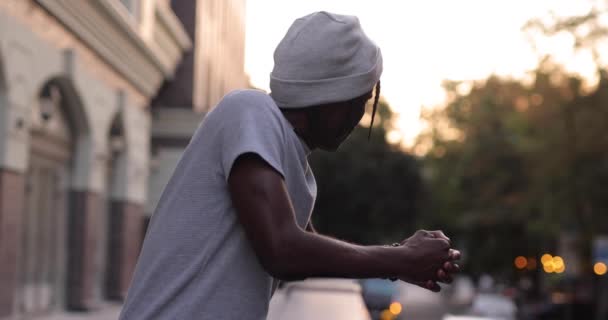 Super cámara lenta hombre africano de pie en la terraza mira a la ciudad — Vídeos de Stock