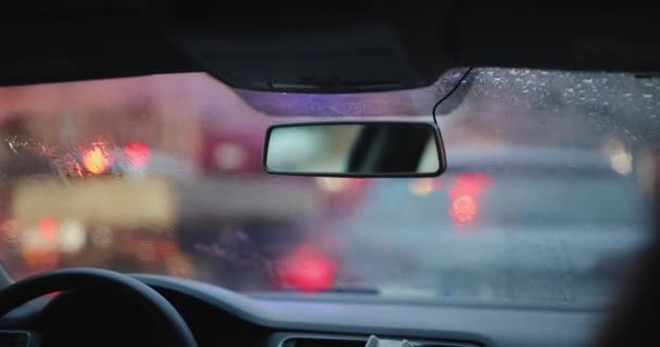 Achteruitkijkspiegel in een auto en voorruit onder regen — Stockvideo