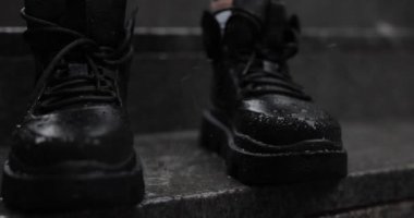 Siyah botların üzerine ağır çekim yağmur yağar