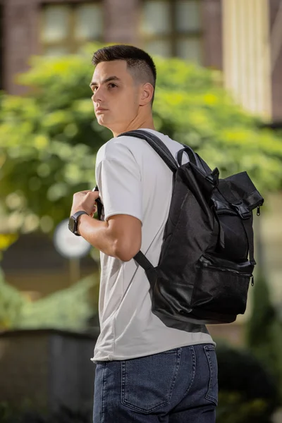 Vista posteriore uomo a piedi in città con zaino in pelle nera — Foto Stock