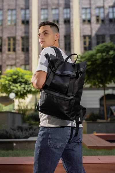 Людина позаду ходить в місті з чорним шкіряним рюкзаком — стокове фото