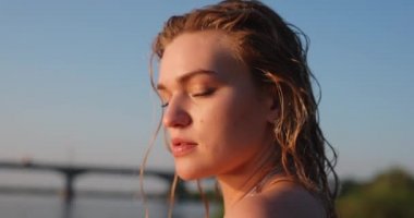 Güzel bir kadın nehre yakından bakar.