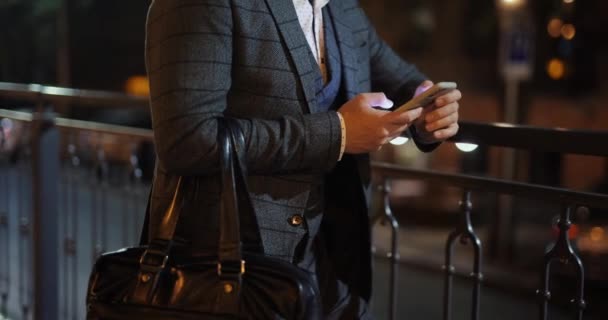 Руки бизнесмена в костюме с помощью смартфона в ночном городе — стоковое видео