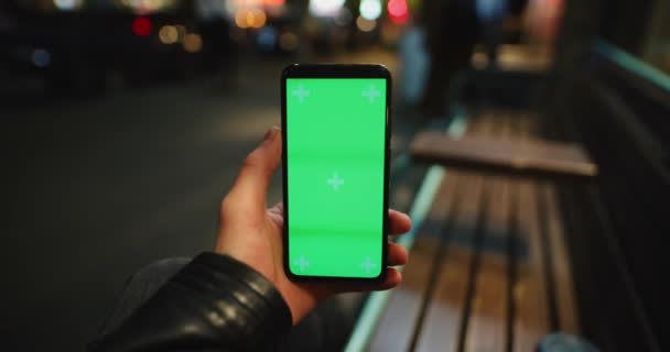 Gece şehrinde yeşil ekranlı bir erkek el telefonu. — Stok video
