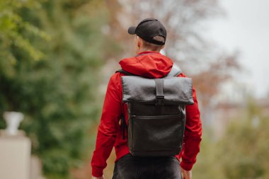 Sırt çantalı adam sonbahar sokağı boyunca yürüyor.