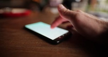 Kafede akıllı telefon kullanan bir erkek.