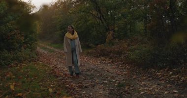 Trençkotlu bir kadın sonbahar ormanlarında yürüyordu.