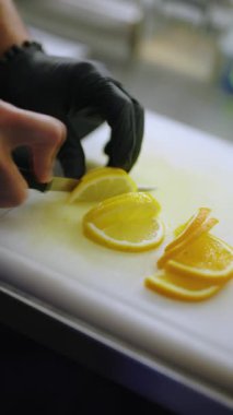 Barmen elleri limonu dilimlere ayırıyor, dikey video.
