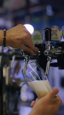 Barmen elleri bardağa bira doldurur, yavaş çekim dikey video.