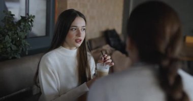 Kadın arkadaşlar kafede konuşuyor ve gülüyorlar, ağır çekimde.