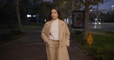 Rahat kadın gece şehir caddesinde yürüyor, ağır çekimde.