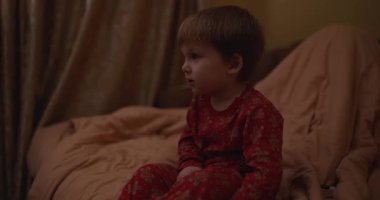 Karanlık bir odada televizyon izleyen küçük bir çocuk.