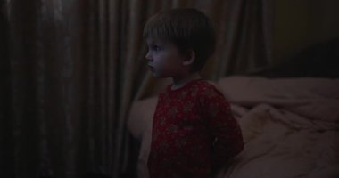Karanlık bir odada televizyon izleyen küçük bir çocuk.