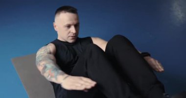 Egzersiz yapan bir adam spor salonunda karın kaslarını şişiriyor.