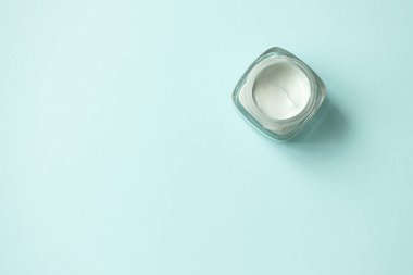 Açık mavi arkaplanda yüz yeşili kil maskesi, fotokopi alanı, üst görünüm. Cilt bakımı güzellik antibakteriyel detoks ürün minimalist düz yatıyordu