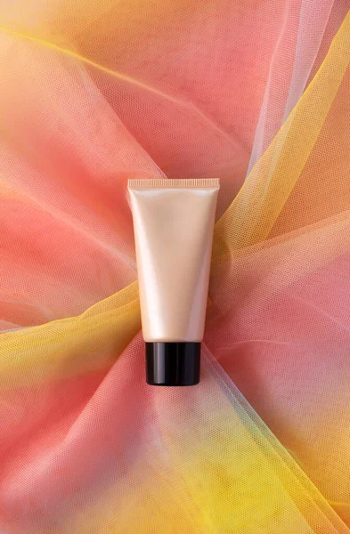 Rör för skönhetsprodukt på färgglada regnbåge satin tyg. CC BB kräm tonal foundation makeup mockup — Stockfoto
