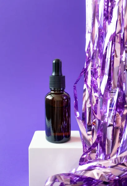 Brown serum jar mockup with pipette and holiday tinsel on cube podium on violet background, vertical. — Foto de Stock