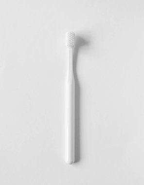 Beyaz arka planda beyaz diş fırçası, dikey. Minimalist diş hijyeni düzlüğü. 