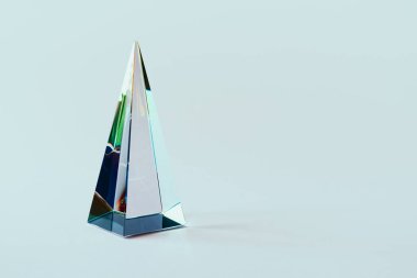 Pastel ışık arka planında renkli güneş ışığı yansıması olan cam piramit prizması