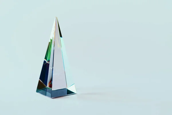 Glazen piramide prisma op pastel lichte achtergrond met kleurrijke zonlicht reflectie — Stockfoto
