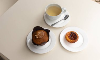 Karamelli kekle kahve molası, pastel de nata ve kafedeki masada bir fincan yeşil çay.