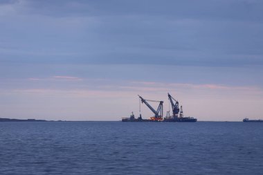 Gün doğumunda denizde büyük vinç gemileri.