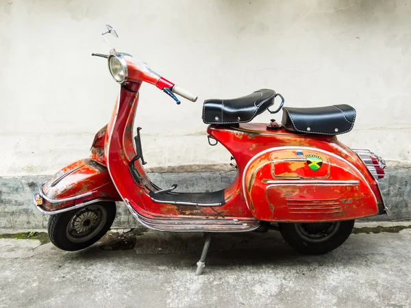 Bir ara sokakta park edilmiş turuncu Vespa scooter.